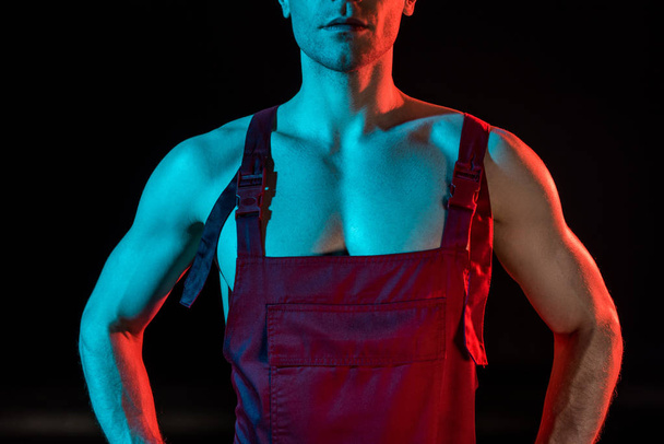 cropped view of sexy shirtless fireman in overall on black - Photo, image