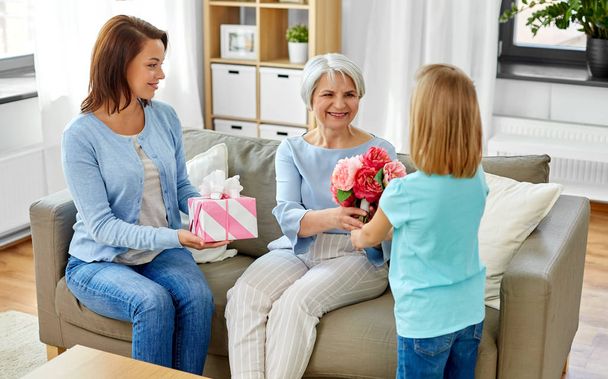 granddaughter giving flowers to grandmother - 写真・画像