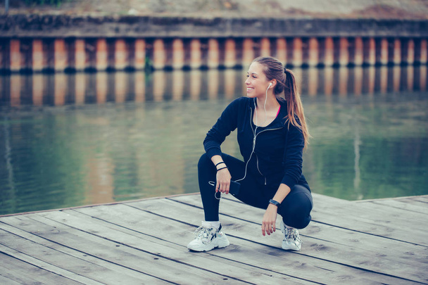 Attractive female runner taking break after jogging  by the rive - Photo, Image