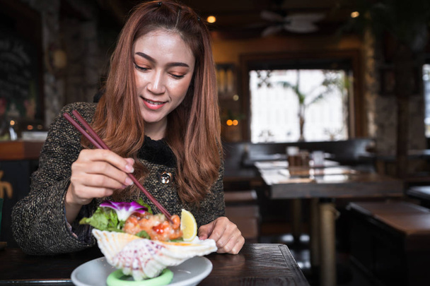 woman eating salmon sashimi spicy salad in restaurant - Photo, image