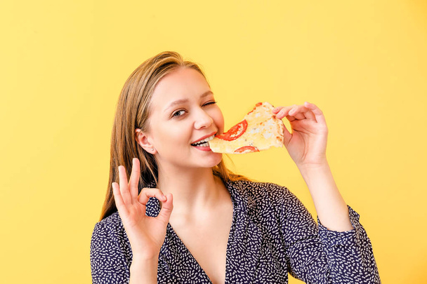 美しい女性食べるおいしいピザ上の色の背景 - 写真・画像