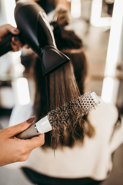 Beautiful brunette woman with long hair at the beauty salon getting a hair blowing. Hair salon styling concept. - Photo, Image