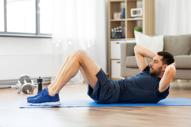 man making abdominal exercises at home - Foto, Imagem