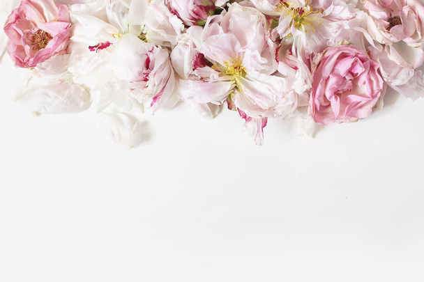 Close up of fading peonies and pink rose flowers petals isolated on white table background. Floral frame composition. Decorative web banner. Styled stock photo. Empty space, flat lay, top view. - Photo, image
