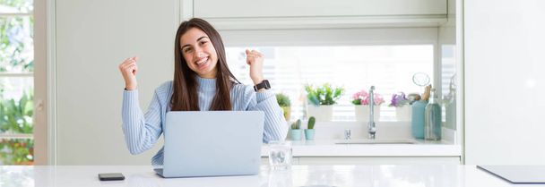 Wide angle picture of beautiful young woman working or studying using laptop screaming proud and celebrating victory and success very excited, cheering emotion - Photo, Image