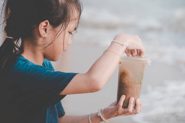 I bambini tengono in mano il bicchiere di plastica che ha trovato sulla spiaggia.
  - Foto, immagini