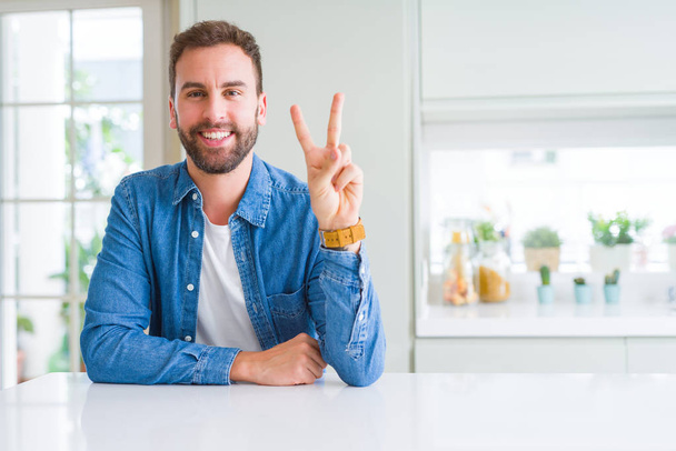 Handsome man at home showing and pointing up with fingers number two while smiling confident and happy. - Foto, immagini