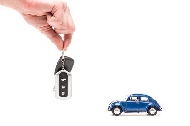 cropped view of man holding key near toy car on white - Foto, imagen