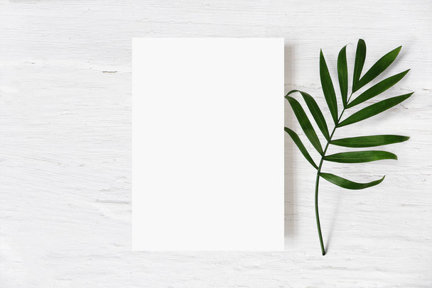 Feminine wedding stationery mock-up, desk scene. Blank greeting card and green palm leaf on white shabby table background. Tropical summer styled photo, web banner. Flat lay, top view. - Fotó, kép