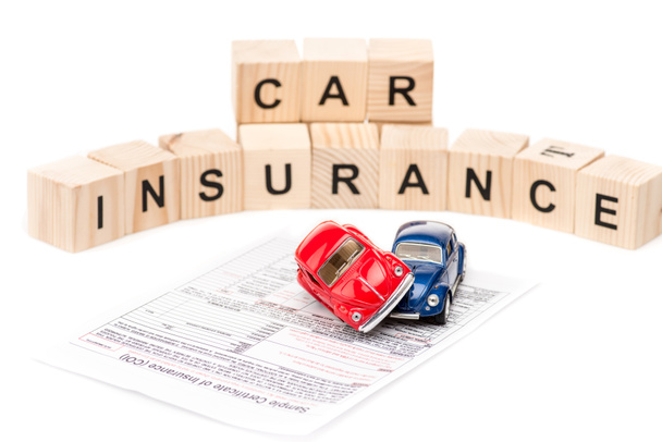 selective focus of toy cars, wooden blocks with letters and insurance certificate isolated on white - Φωτογραφία, εικόνα