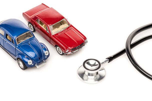 red and blue toy cars and stethscope isolated on white surface - Foto, imagen