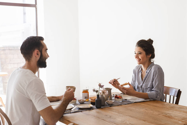Image of caucasian brunette couple eating together at table whil - 写真・画像