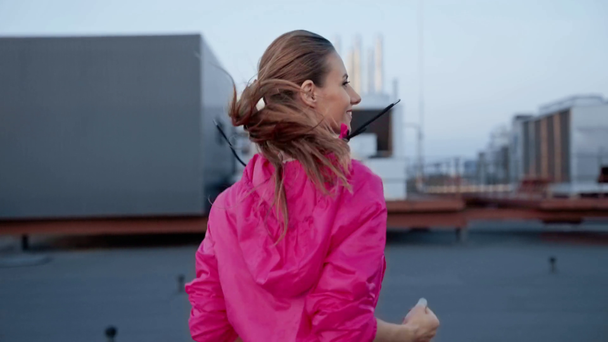 schöne Sportlerin in Sportbekleidung läuft auf dem Dach mit Lächeln - Filmmaterial, Video