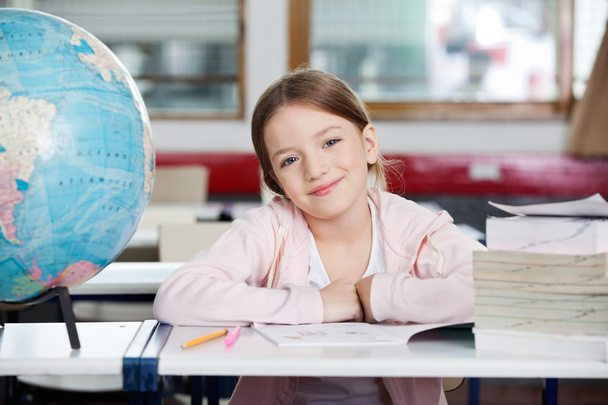 Cute Schoolgirl Smiling With Globe And Books At Desk - Photo, image