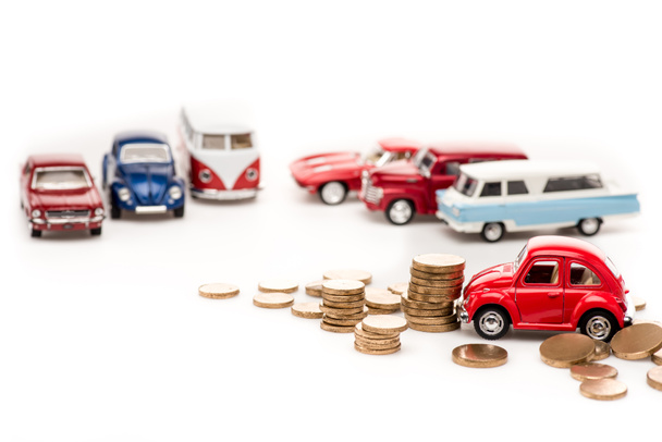 selective focus of colorful toy cars and golden coins on white - Фото, зображення