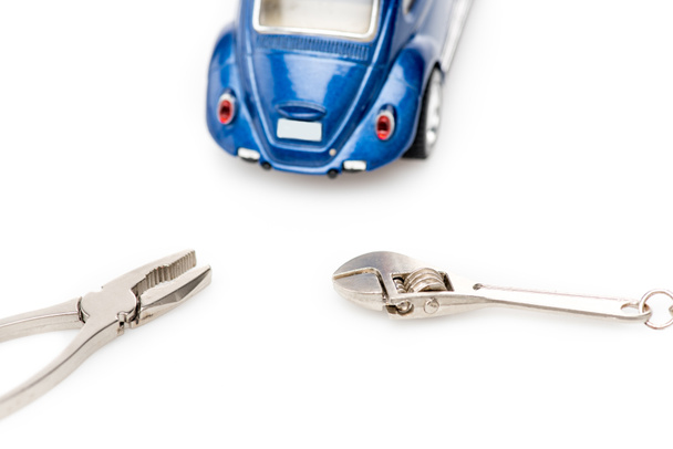 blauwe speelgoed auto, moersleutel en Tang op wit oppervlak - Foto, afbeelding