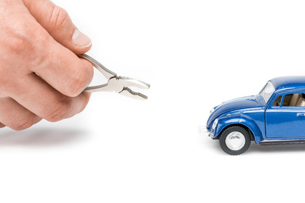 cropped view of man holding pliers and blue toy car on white - Photo, Image