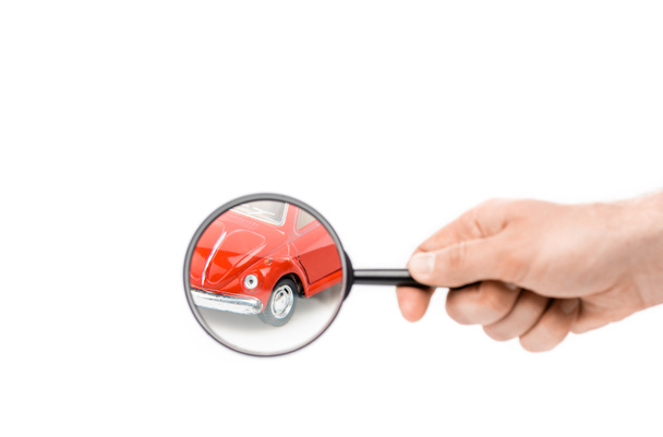 cropped view of man holding magnifier in front of toy car isolated on white - Фото, зображення