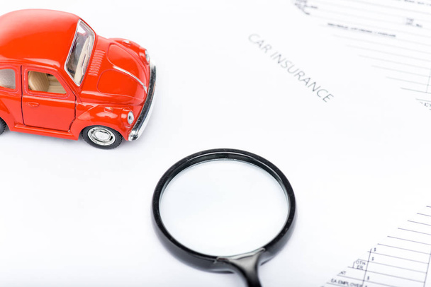 red toy car, magnifying glass and insurance documents - Foto, Bild