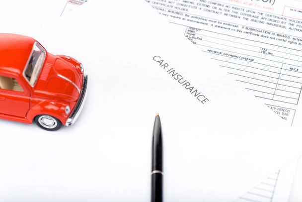red toy car, black pen and insurance documents - 写真・画像