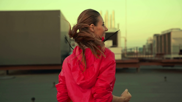 beautiful sportswoman in sportswear running on rooftop with smile - Footage, Video