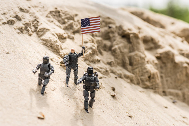 játék katonák fegyverrel állt a homok és a gazdaság amerikai zászló - Fotó, kép
