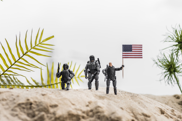 砂丘にアメリカ国旗を掲げるおもちゃの兵士の選択的な焦点 - 写真・画像