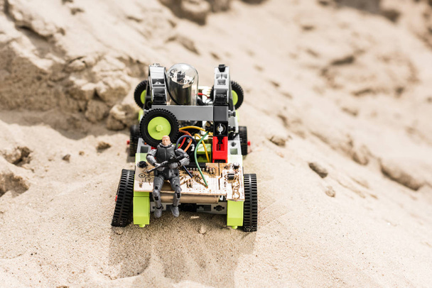 Plastický voják hraček, který sedí se zbraní na voze na písečné duně - Fotografie, Obrázek