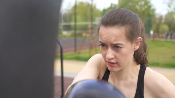 Young woman boxer training with punching bags on street city training ground. Steady shot, slow motion. Face close up - Materiaali, video