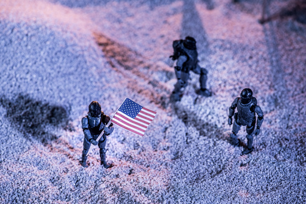 Ansicht von Spielzeug-Astronauten mit amerikanischer Flagge auf kosmischem Planeten - Foto, Bild