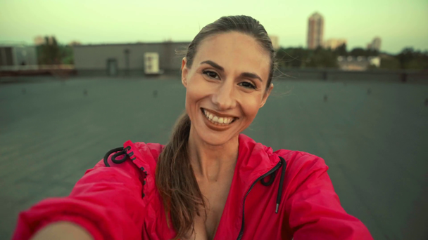 mooie Sportvrouw staande op het dak, glimlachend, zwaaien Hallo en praten op video chat - Video