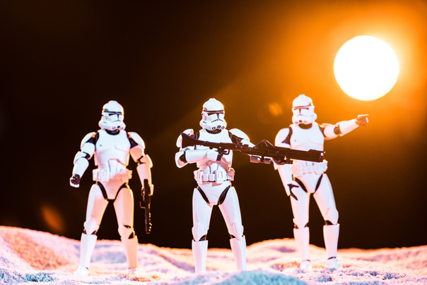 white imperial stormtroopers with guns on cosmic planet with sun on background - Foto, imagen