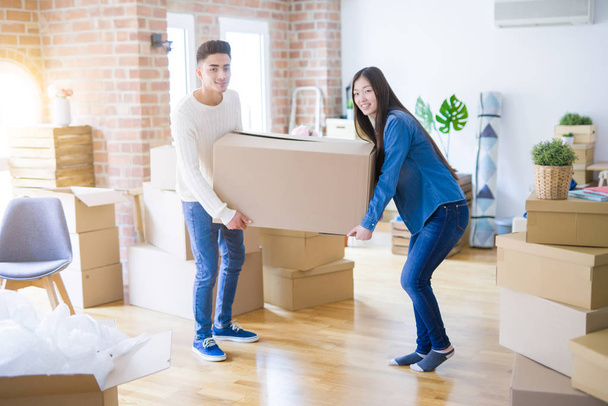 Bonito jovem casal asiático olhando feliz, segurando uma grande caixa de papelão sorrindo animado movendo-se para uma nova casa
 - Foto, Imagem