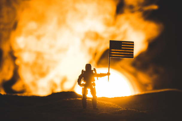 Toy soldaat silhouet met Amerikaanse vlag op de planeet met zon in rook  - Foto, afbeelding