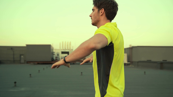 sportember a sárga sportruházat bemelegítés, emelt kezekkel, könyök félre és nyújtás a tetőn edzés előtt - Felvétel, videó