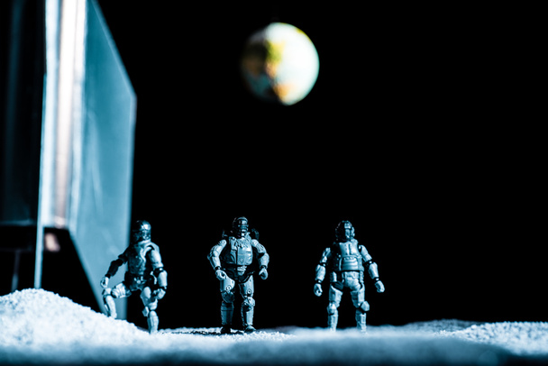 soldados de juguete de pie en el espacio sobre fondo negro con el planeta tierra
 - Foto, Imagen