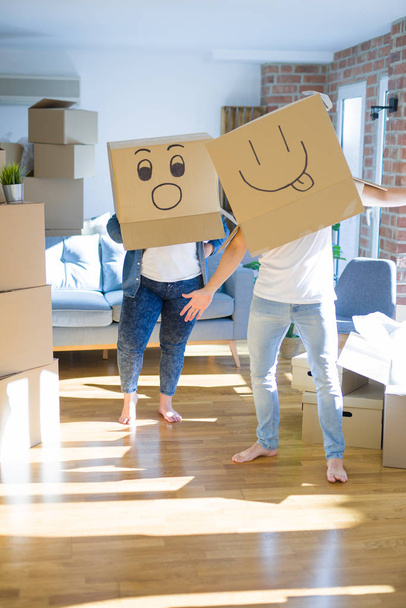 Verrücktes Paar trägt Pappschachteln mit lustigen Emoji-Gesichtern über dem Kopf und hat Spaß am neuen Haus - Foto, Bild