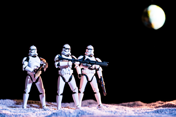white imperial stormtroopers with guns in space on black background with planet Earth - Fotografie, Obrázek