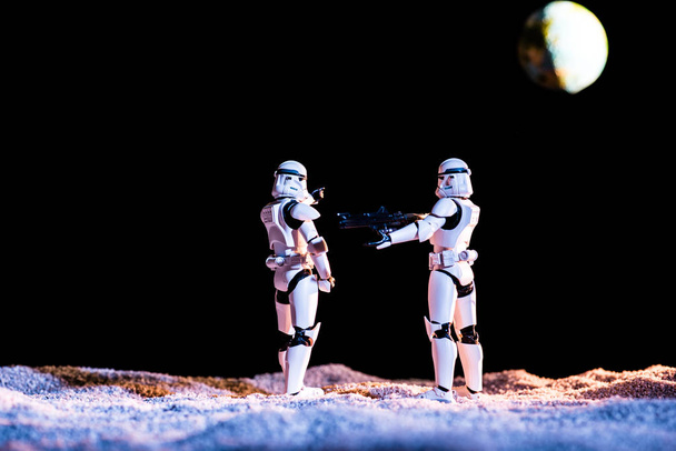 white imperial stormtroopers with gun on black background with planet Earth - Foto, Imagem