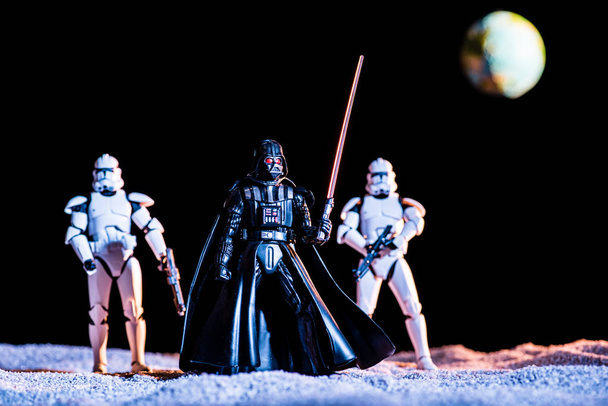 two white imperial stormtroopers with guns and Darth Vader with lightsaber with planet Earth on background - Photo, image
