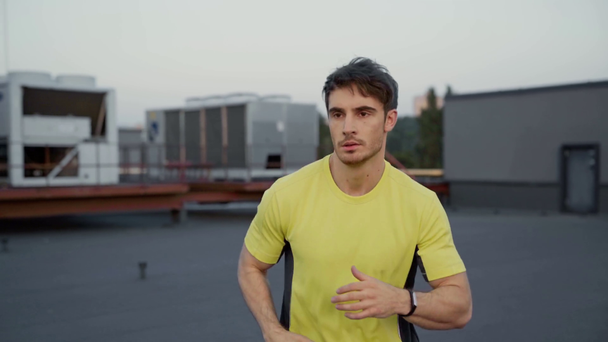knappe sportman in gele sportkleding die op het dak draait - Video
