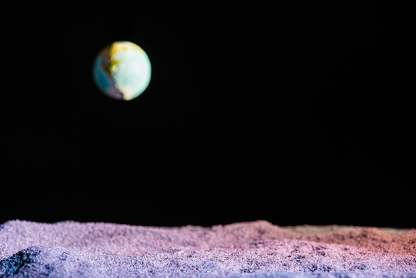 sandy ground with blurred planet Earth in space isolated on black with copy space - Фото, изображение