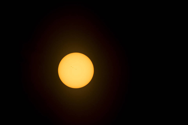 Telephoto image of the sun taken through a light protective filter revealing sun spots on the suns surface. - Photo, Image