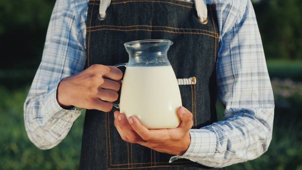 Der Bauer hält einen Krug mit Milch in der Hand. Konzept für Bio-Produkte - Foto, Bild