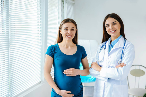 Vrouwelijke gynaecoloog werken met zwangere vrouw in kliniek - Foto, afbeelding