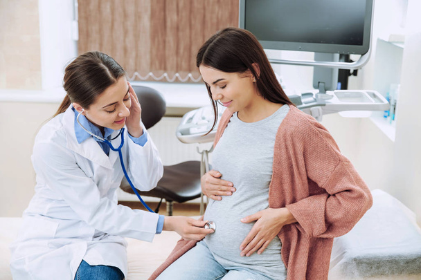 Female gynecologist working with pregnant woman in clinic - Фото, изображение