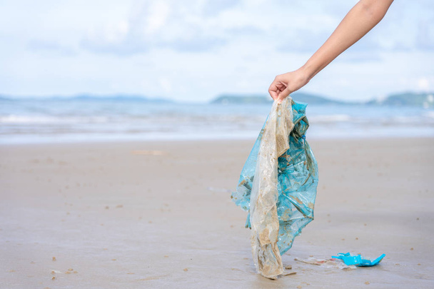 Жінка рука збирає використаний пластиковий пакет на піщаному пляжі, Кліні
 - Фото, зображення