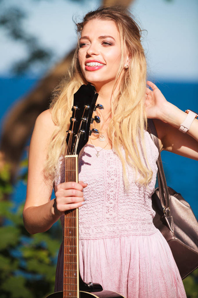Blonde woman with acoustic guitar on seaside - 写真・画像