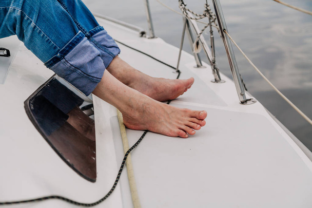 Bare feet stand on deck of  yacht - Photo, image