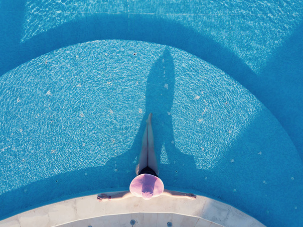 Nuori nainen ottaa aurinkoa uima-altaassa
 - Valokuva, kuva